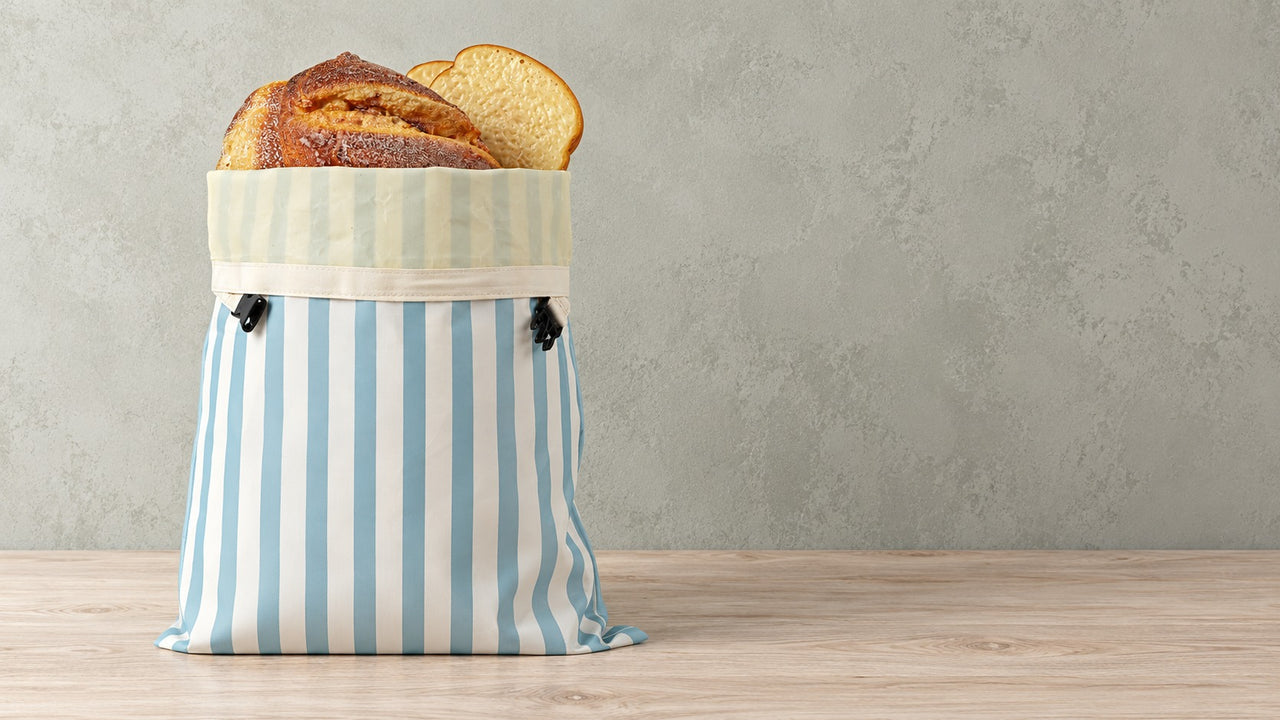 Bread bag closed with its buckles against a sage wall